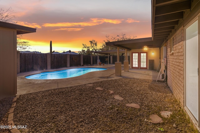 pool at dusk featuring a patio area and french doors