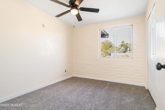 unfurnished room with ceiling fan, brick wall, and carpet