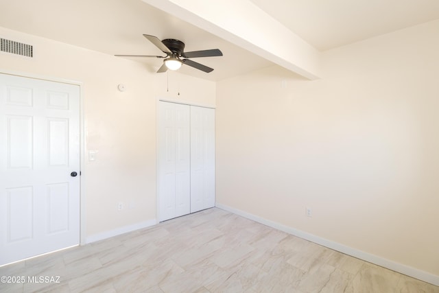 unfurnished bedroom with ceiling fan, beam ceiling, and a closet