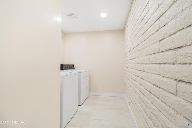 laundry area with brick wall and washing machine and clothes dryer