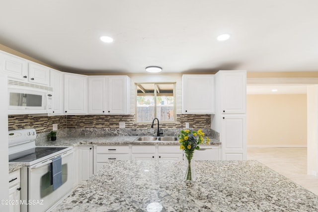 kitchen with sink, white cabinetry, light stone counters, tasteful backsplash, and white appliances