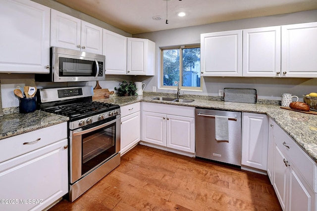 kitchen with sink, light stone counters, appliances with stainless steel finishes, light hardwood / wood-style floors, and white cabinets