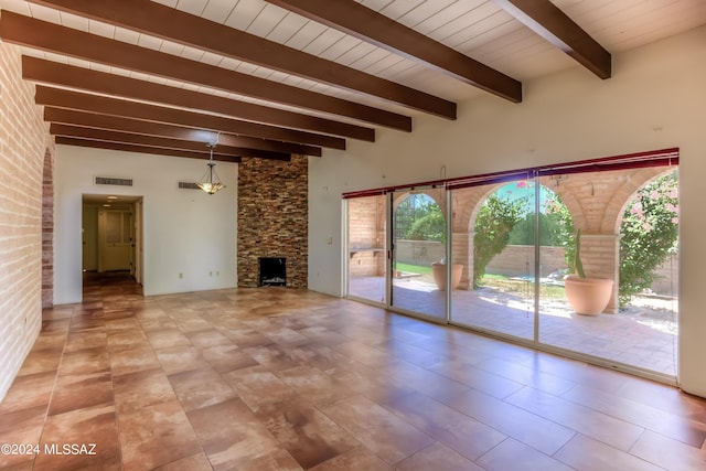 unfurnished living room with a stone fireplace and beam ceiling