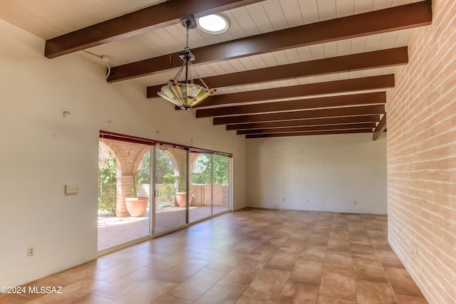 unfurnished room featuring beamed ceiling and brick wall