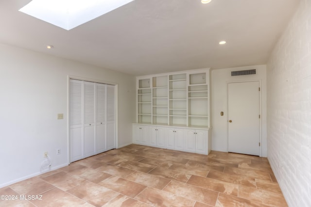 unfurnished bedroom with a skylight and a closet