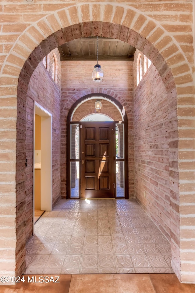 entryway featuring a high ceiling and brick wall