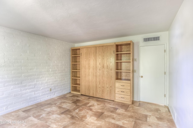 unfurnished bedroom featuring brick wall