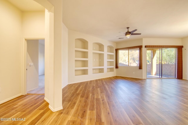 unfurnished living room with built in shelves, light hardwood / wood-style floors, and ceiling fan