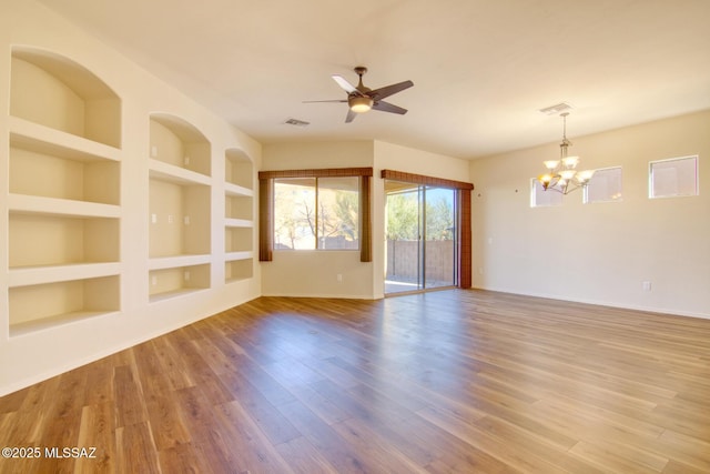 spare room with built in shelves, wood-type flooring, and ceiling fan with notable chandelier