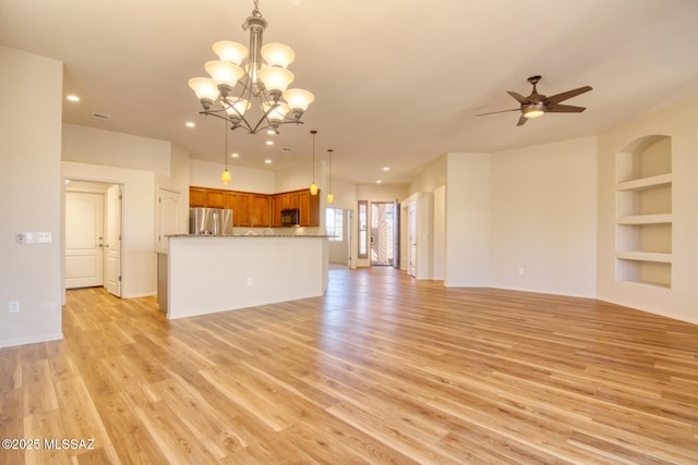 unfurnished living room featuring ceiling fan with notable chandelier, built in features, and light hardwood / wood-style floors