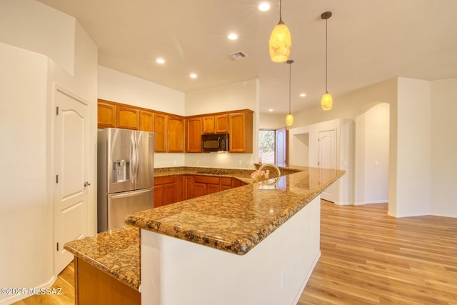 kitchen featuring dark stone countertops, pendant lighting, light wood-type flooring, and black appliances