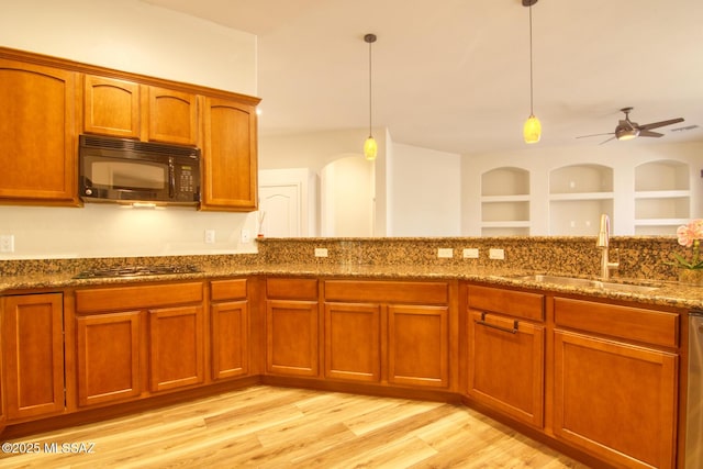 kitchen with pendant lighting, sink, gas cooktop, light hardwood / wood-style flooring, and dark stone countertops