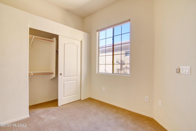 unfurnished bedroom featuring light colored carpet and a closet