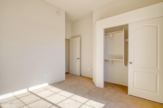 unfurnished bedroom with light colored carpet and a closet