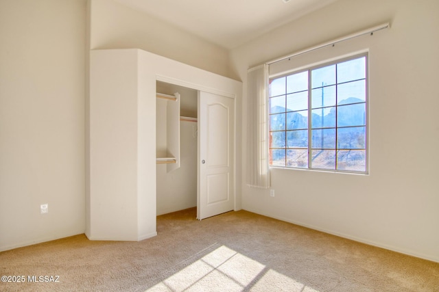 unfurnished bedroom with light colored carpet and a closet