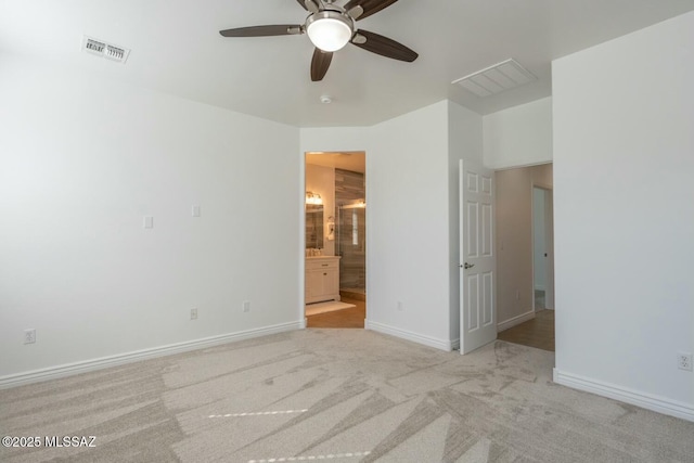 interior space with light carpet, connected bathroom, and ceiling fan