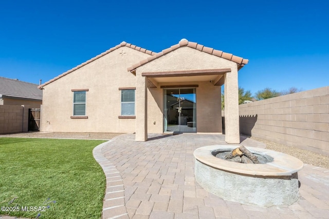 rear view of house featuring an outdoor fire pit, a patio, and a lawn