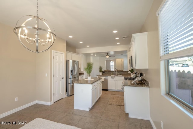 kitchen featuring white cabinetry, stainless steel appliances, a healthy amount of sunlight, a kitchen island, and decorative light fixtures