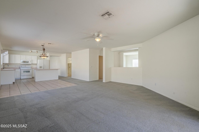 unfurnished living room with ceiling fan, light colored carpet, and sink