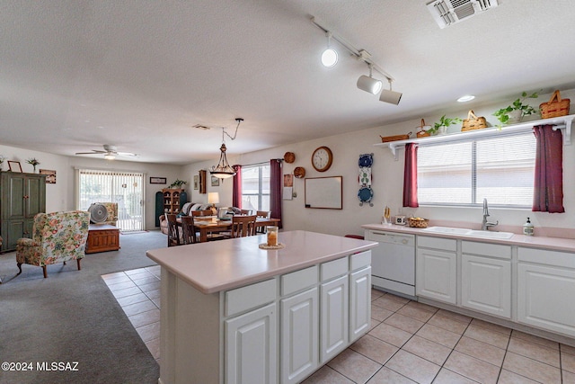 kitchen featuring sink, a center island, white dishwasher, white cabinets, and decorative light fixtures