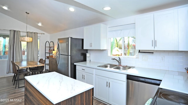 kitchen featuring appliances with stainless steel finishes, decorative light fixtures, lofted ceiling, sink, and white cabinets