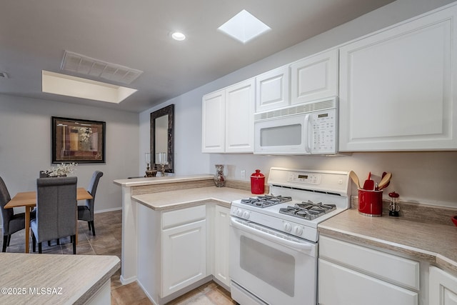 kitchen with a skylight, white cabinets, white appliances, and kitchen peninsula