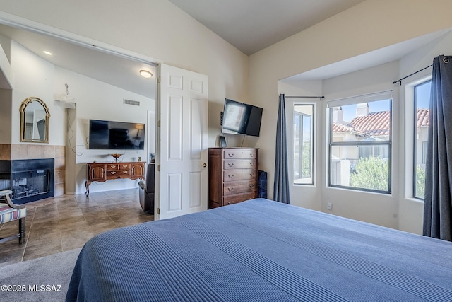 tiled bedroom with vaulted ceiling and a fireplace