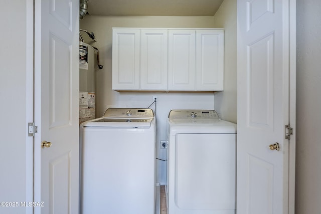 clothes washing area featuring washer and clothes dryer and cabinets