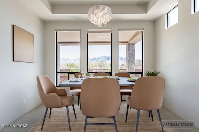 dining area with a raised ceiling, a mountain view, and a notable chandelier