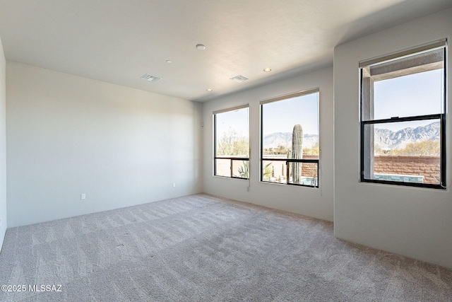 carpeted empty room with visible vents, a mountain view, and recessed lighting