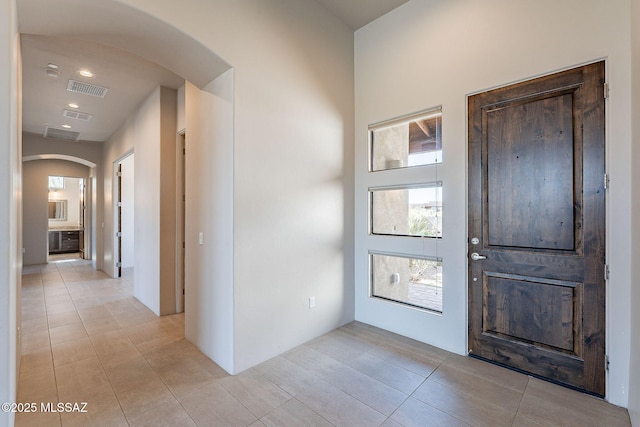 foyer with arched walkways, visible vents, and light tile patterned floors