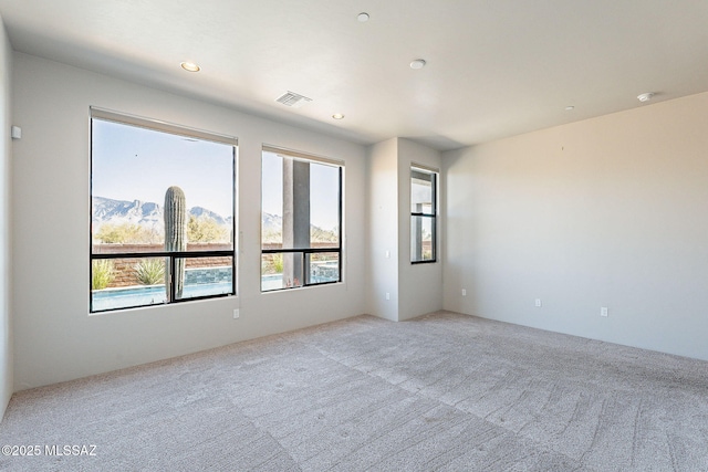 spare room with visible vents, recessed lighting, a mountain view, and light colored carpet