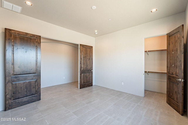 unfurnished bedroom featuring visible vents, a walk in closet, and recessed lighting