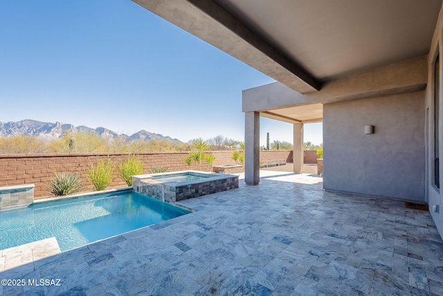 view of swimming pool featuring a pool with connected hot tub, a patio area, a fenced backyard, and a mountain view