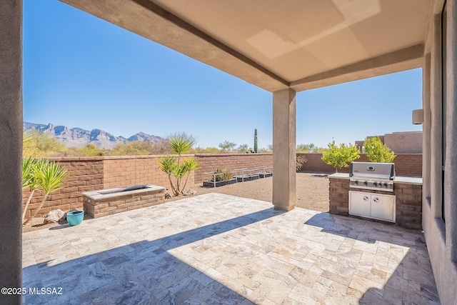 view of patio featuring a fenced backyard, a mountain view, an outdoor kitchen, and area for grilling