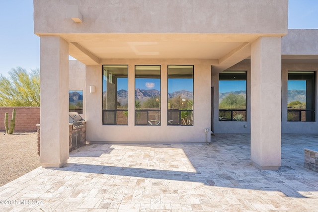 doorway to property featuring a patio area, area for grilling, fence, and stucco siding