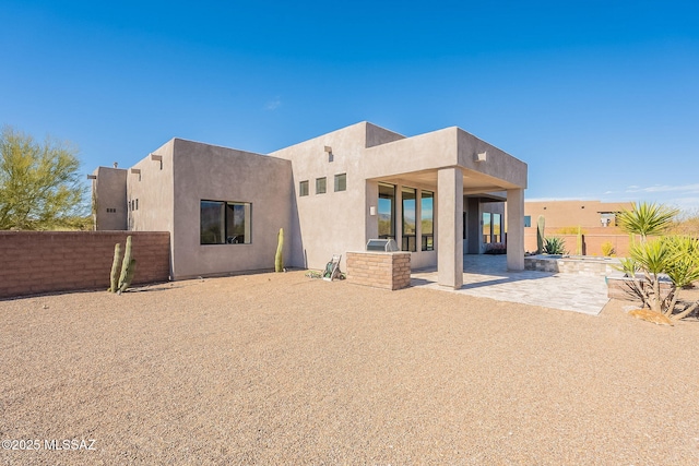 rear view of property featuring a patio area, a fenced backyard, and stucco siding