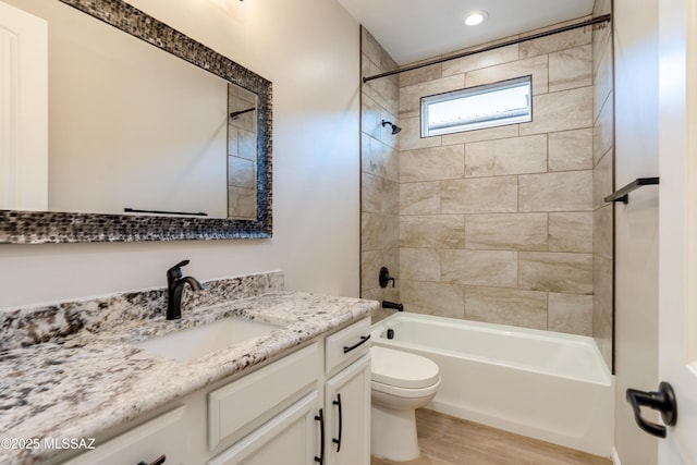 full bathroom featuring vanity, hardwood / wood-style flooring, toilet, and tiled shower / bath