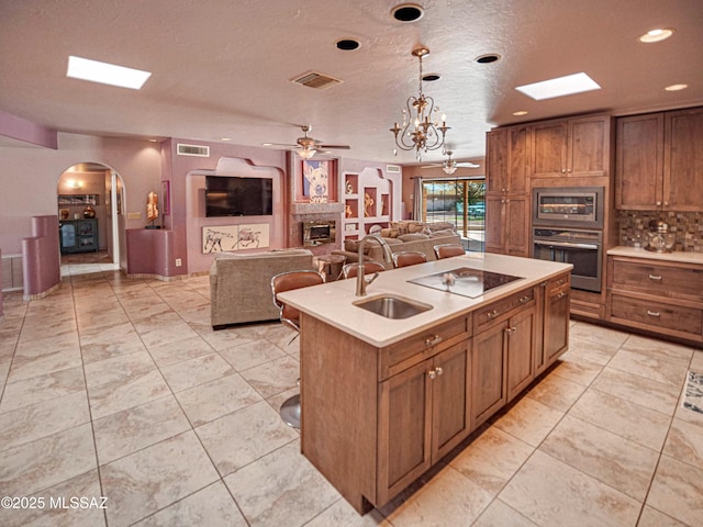 kitchen featuring light countertops, visible vents, appliances with stainless steel finishes, a sink, and an island with sink