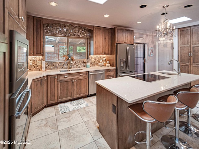 kitchen featuring a sink, stainless steel appliances, light countertops, and a kitchen breakfast bar