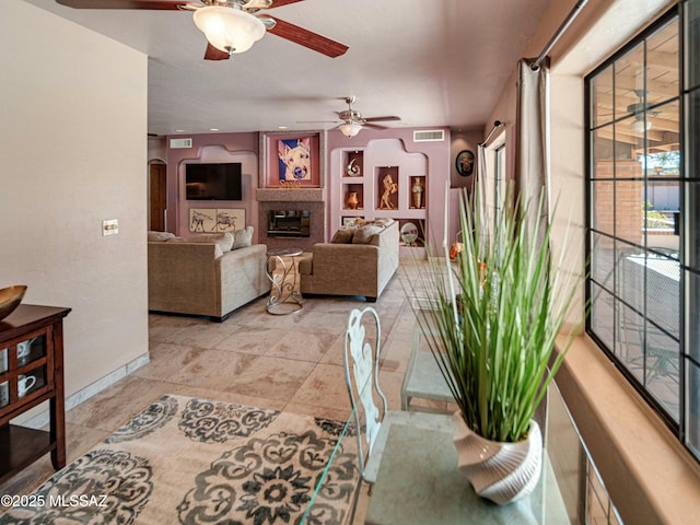 living area with baseboards, visible vents, and a glass covered fireplace