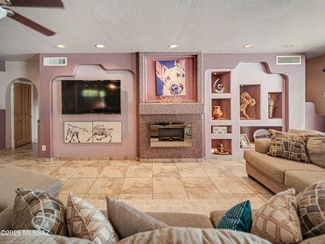 living room with built in features, visible vents, and a textured ceiling