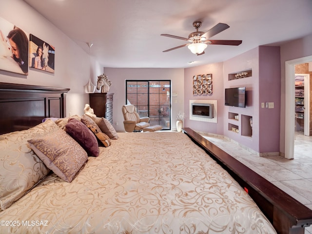 bedroom with a ceiling fan, a fireplace, baseboards, and light tile patterned floors