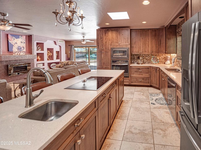 kitchen with pendant lighting, light countertops, open floor plan, a sink, and black appliances