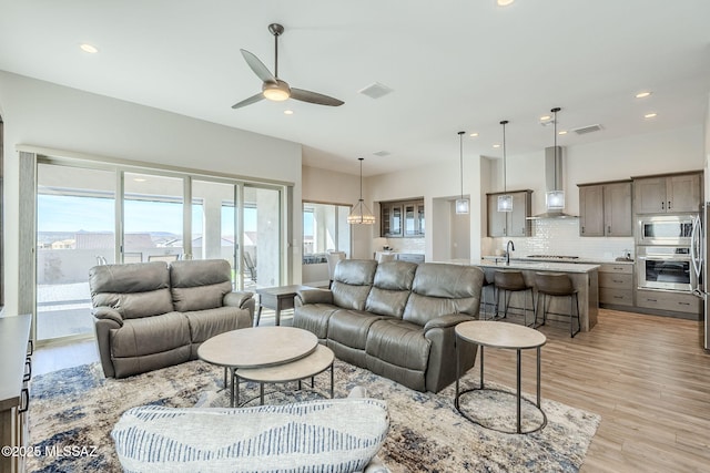 living room featuring ceiling fan, sink, and light hardwood / wood-style flooring