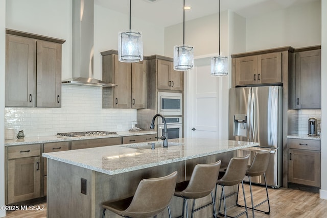 kitchen with stainless steel appliances, light stone countertops, sink, and decorative light fixtures