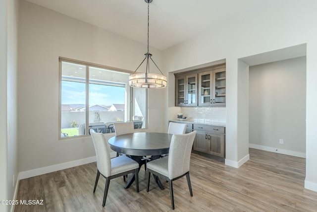 dining space featuring lofted ceiling, light hardwood / wood-style floors, and an inviting chandelier