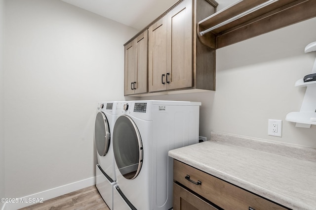 clothes washing area featuring cabinets, independent washer and dryer, and light hardwood / wood-style floors