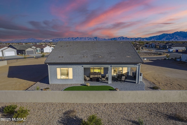 back house at dusk featuring an outdoor living space, a mountain view, and a patio