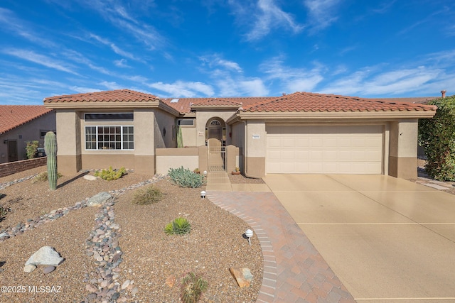 mediterranean / spanish home featuring a garage, concrete driveway, a gate, and stucco siding